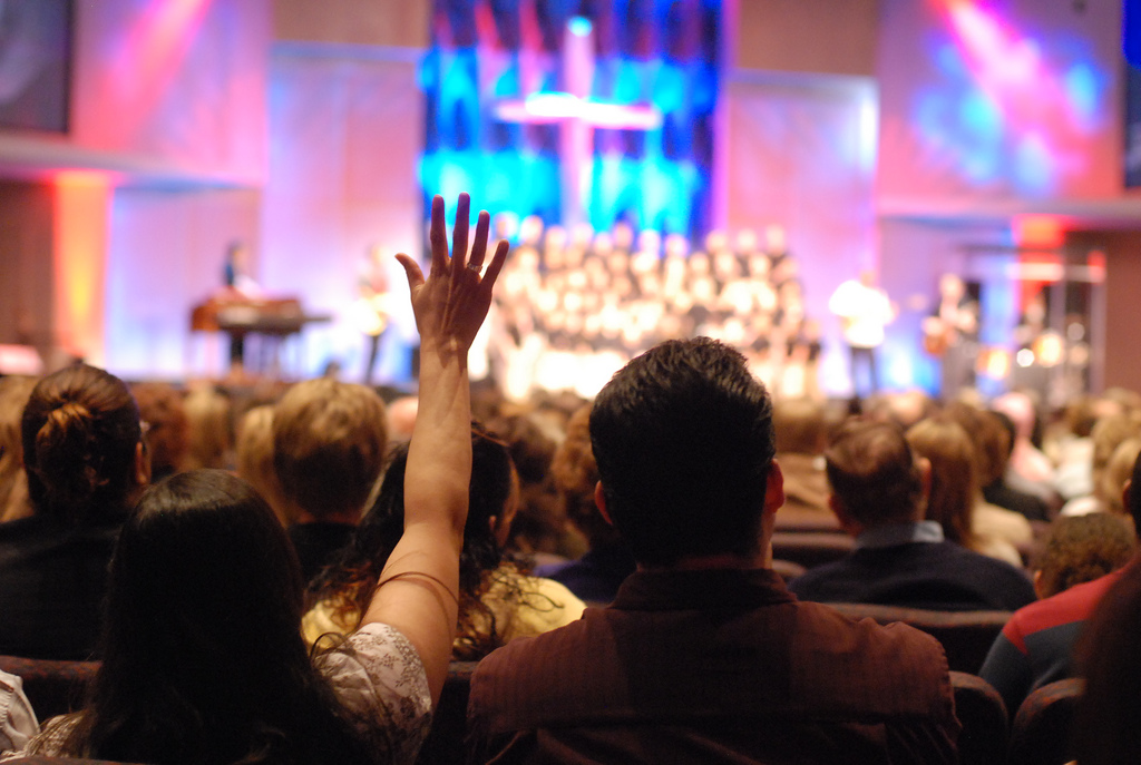 image of woman with hand in the air at church