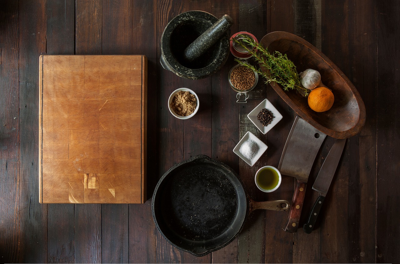 image of cooking ingredients, pot, and grinder on brown wood table
