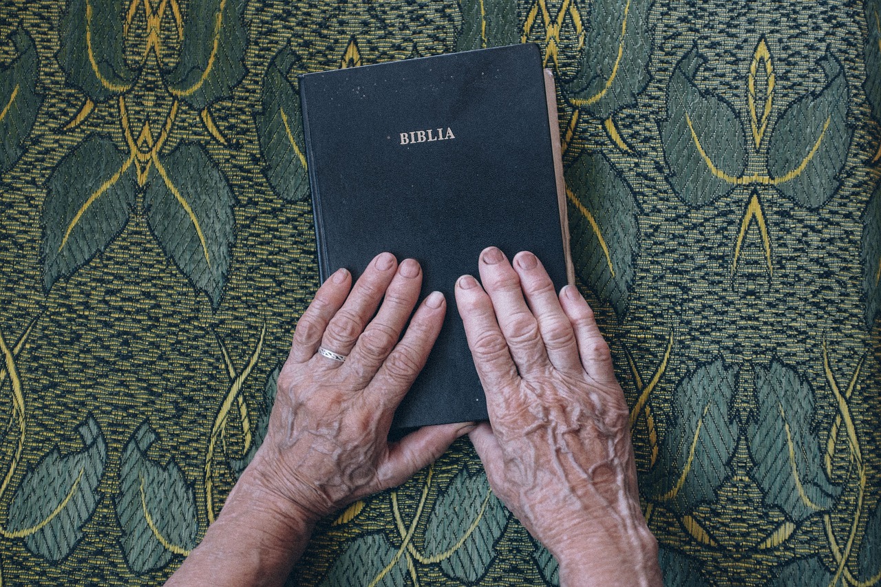 image of bible begin held by two hands atop a fabric tablecloth