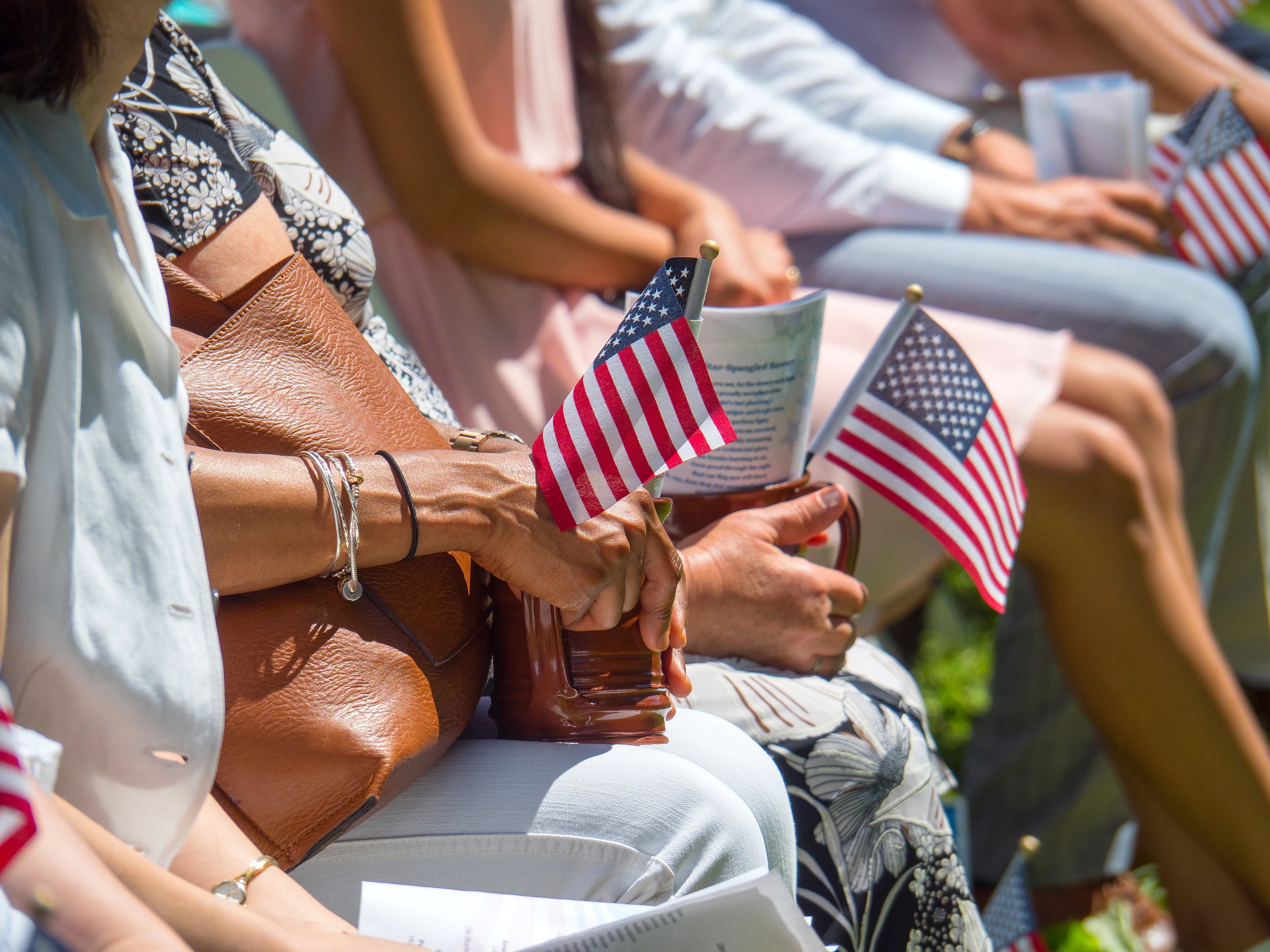 close up of people's hands holding small American flags