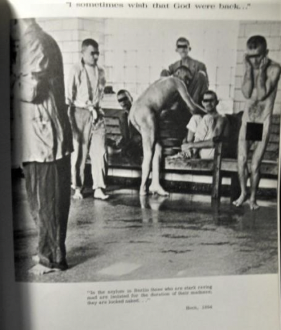 Black and white photograph of five 'residents' and two workers in an institution for the disabled. The residents have their faces and genitals obscured by black boxes.